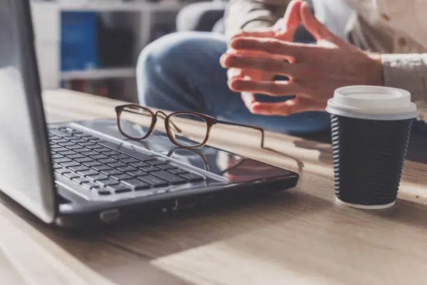 person sitting with laptop, glasses and cup of coffee -copywriter job