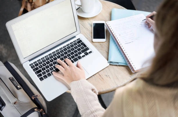 Person working on a laptop, taking notes at a table. -content creation companies