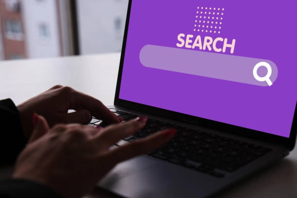 Person typing on laptop with purple search bar on screen. -how does seo and content marketing work together